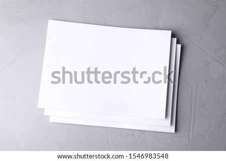 Blank paper sheets on light grey stone background, top view. Mock up for design