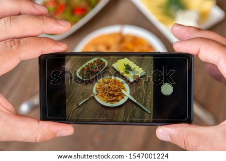 Smartphone photo of food.Mans hands make phone photography of l traditional meals. lunch or dinner.Beef stroganoff. For social media, blogging.  Top view mobile phone.