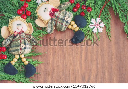 Green spruce branches. Brown wooden background. White, red, multi-colored Christmas toys. Decorations for Christmas tree made of wood and ceramics. Festive fun concept. Congratulatory backdrop. 