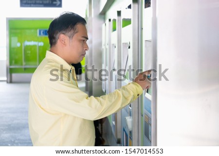 Asian man using vending ticket machines to take the skytrain in Thailand