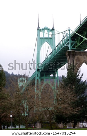 A vertical low angle shot of the famous St. Johns Bridge surrounded by a forest in Portland, Oregon, United States