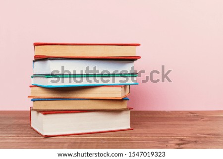 Simple Simple composition of many hardback books, unprocessed books on a wooden table and a pale pink background. back to school. Copy space Education.
