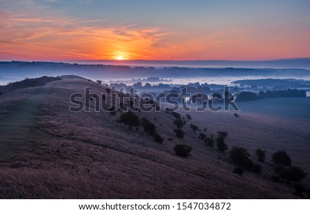 sunrise and mist in the valley over the Ivinghoe hills in Buckinghamshire south east England Royalty-Free Stock Photo #1547034872