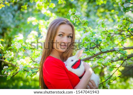 Beautiful girl with a rabbit. Woman in a red dress with a decorative hare. Animals and people.
