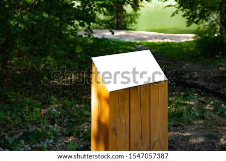 Blank horizontal information sign on green grass in park on wooden stand