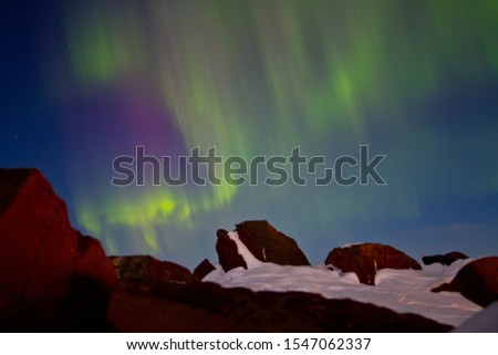 Arctic landscape with aurora. Northern lights (aurora borealis) over a rocky mountain peak. Beautiful multi-colored flashes in the night sky. Chukotka, Siberia, Far North of Russia.