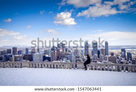 Young woman looking out over downtown Montreal from a snow-covered observation area in Mount Royal Park - Montreal, Canada (Winter) 