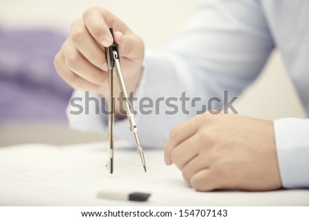 Hands of engineer working with compasses