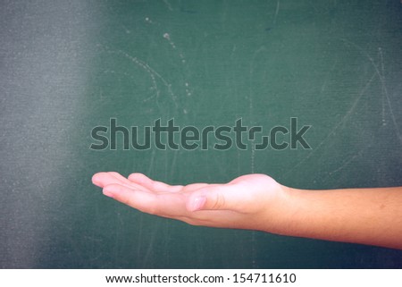 child's hand holding or showing your product in front of blackboard
