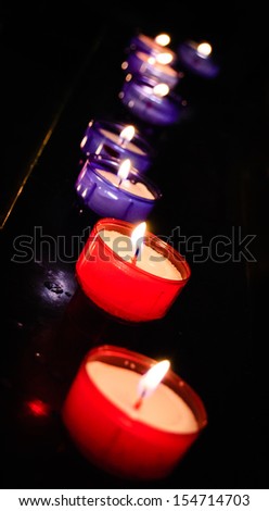 Row of red and violet candles in the church. Selective focus on second red candle.