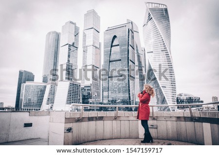 Girl in an orange coat on the background of Moscow city.