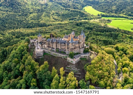 Aerial panorama of Burg Hohenzollern (Hohenzollern castle) with hills and villages surrounded by forests with beautiful foliage Royalty-Free Stock Photo #1547169791