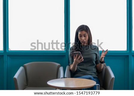 Beautiful cute Asian young businesswoman in the cafe, using smartphone. Young Asian Traveler. Asian women feeling surprise while looking at her phone. Asian woman holding mobile phone.