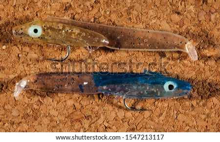 Colorful fishing hook, plummet and plastic baits for catching fish, with isolated on natural brown background. Fishing and hobbies concepts. Horizontal close-up detail.