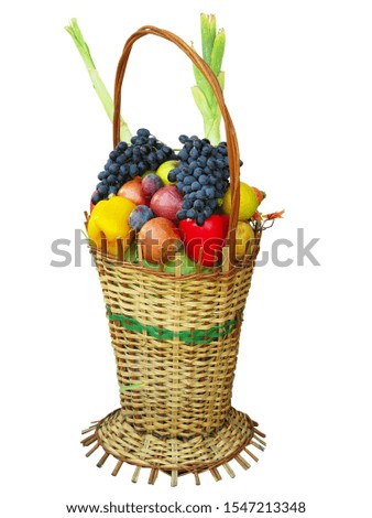 Wicker basket filled with colorful organic vegetables fresh harvest plums, grapes and apples isolated on white
