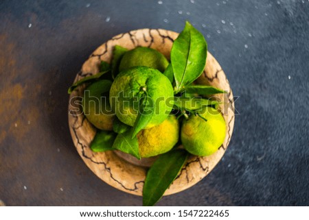 Fresh tangerines with leaves on plate with holiday decor on stone background with copy space