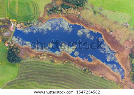 aerial view to blue grosser eschacher weiher pond with green algae and meadow