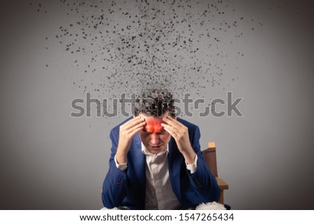 Stressed man having severe headache while his head is falling into pieces. 