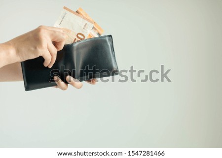Close-up of hands holding a short wallet and one hand bring out the money in the currency of EURO or EUR; from the wallet to pay for something on white background with copy space.