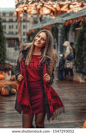 A girl walks through the autumn city. Pumpkins decorate the streets