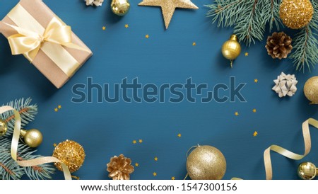 Christmas card with pine tree branches, gifts, golden decorations over blue background. Flat lay, top view, copy space. Christmas frame, New year banner mockup
