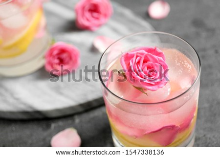 Delicious refreshing drink with lemon and rose on grey table, closeup