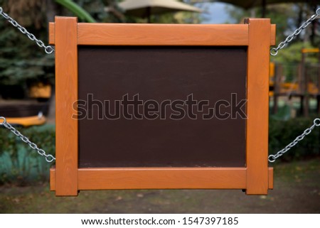 wooden brown orange sign close up on a chain against the blurred background of the Park.  mockup