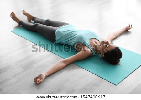 Young woman practicing corpse asana in yoga studio. Savasana pose Royalty-Free Stock Photo #1547400617