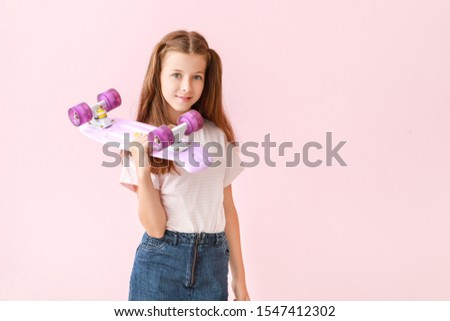 Stylish little girl with skateboard on color background