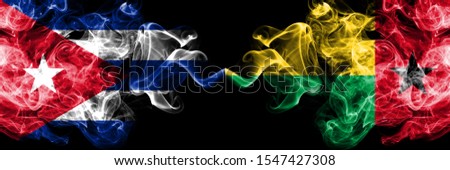 Cuba, Cuban vs Guinea Bissau smoky mystic flags placed side by side. Thick colored silky travel abstract smokes banners 