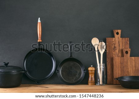 Kitchen utensils dark background with cast iron black kitchenware, front view of home kitchen table top Royalty-Free Stock Photo #1547448236
