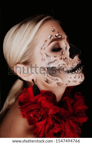 Portrait of a woman with sugar skull makeup over red background. Halloween costume and make-up.  Royalty-Free Stock Photo #1547494766