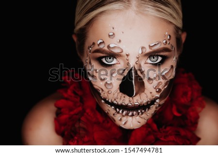 Portrait of a woman with sugar skull makeup over red background. Halloween costume and make-up.  Royalty-Free Stock Photo #1547494781