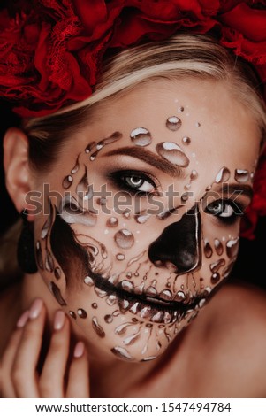 Portrait of a woman with sugar skull makeup over red background. Halloween costume and make-up. Royalty-Free Stock Photo #1547494784
