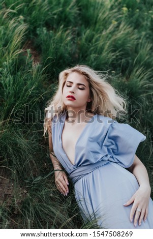 young girl dressed in an elegant long lilac dress. A neat hairstyle of blond hair, blonde, walks across the field in the forest. Happy escaped the mysterious princess. Royalty-Free Stock Photo #1547508269