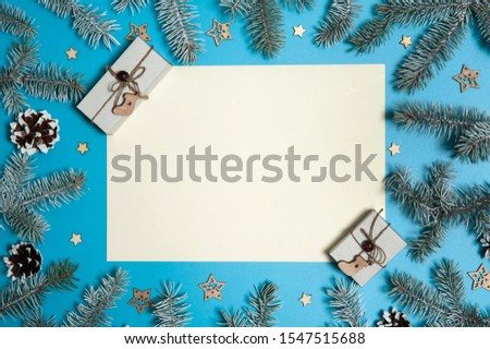 Christmas composition. Paper blank, fir branches, pine cones, gift boxes and wooden decorative stars on a light blue background. Christmas, winter, New year.