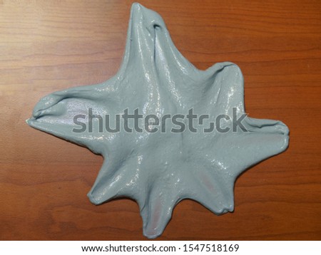 Photography of blue homemade slime on the table. Shape of blue starfish. Concepts of play and childhood