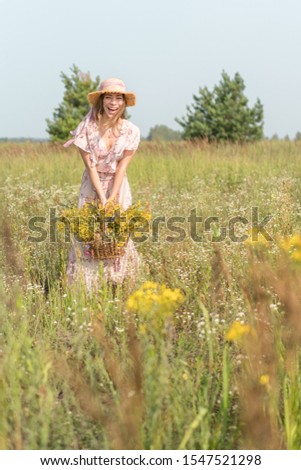 girl with a basket of flowers and a straw hat in a summer field