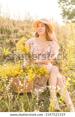 girl with a basket of flowers and a straw hat in a summer field