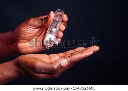 close up hands of afro male useing antiseptic in studio black background. Royalty-Free Stock Photo #1547526605