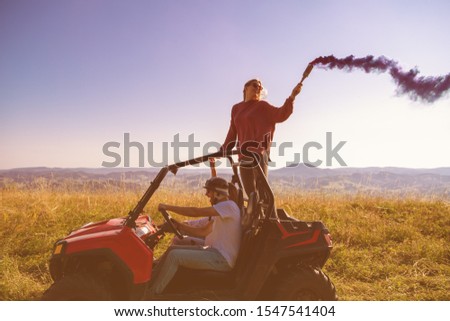 group of young happy excited people having fun enjoying beautiful sunny day holding colorful torches while driving a off road buggy car on mountain nature