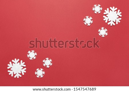 Christmas composition, group of little white felt snowflakes on burgundy red background, copy space. Festive, New Year concept. Horizontal, flat lay. Minimal style. Top view.