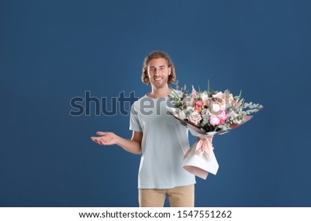 Young handsome man with beautiful flower bouquet on blue background