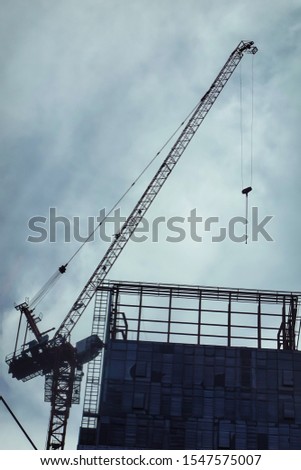Construction site with cranes against a dark blue sky with white clouds. Bottom view of the construction of a high-rise building. With Silhouette high contrast as a concept.