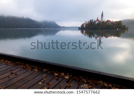 Photo of lake Bled taken from the boardwalk early in the morning with small island and church in the background