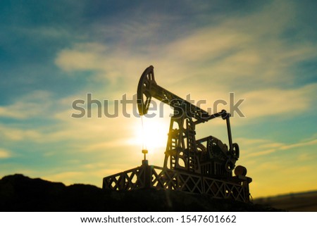 Oil pump on a sunset background. Oil production, fuel, natural resources.