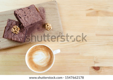Sweet tasty brownies covered with cocoa with walnuts and a cup of cappuccino on a wooden background top view. Spase for text. Background. Closeup