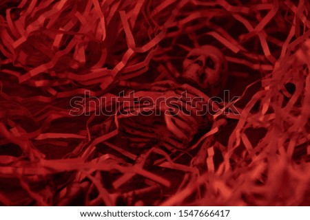 skeleton figurine in tinsel from white paper on a wooden background with a red filter
