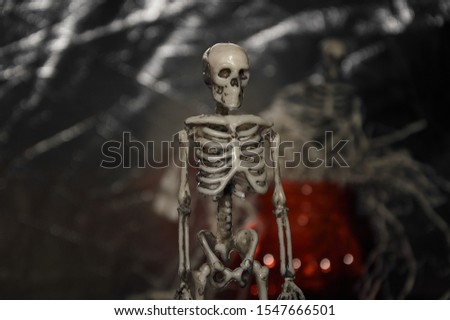 figurine of a skeleton in tinsel from white paper in a cup in the shape of a pumpkin