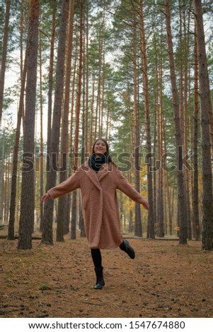 Beautiful happy woman dancing in the autumn forest.